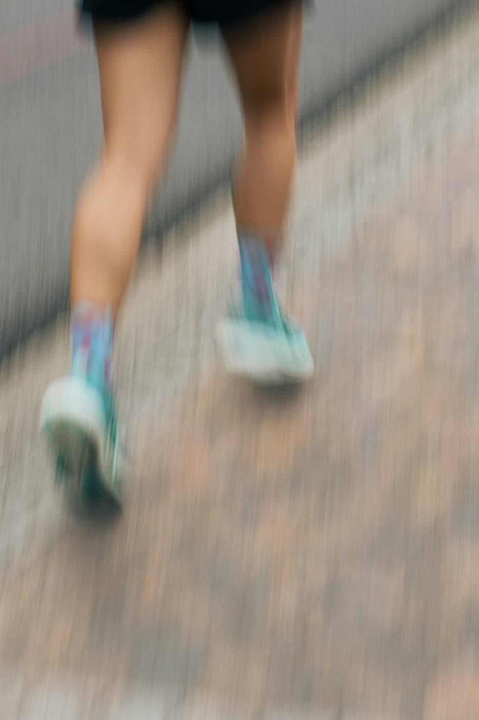 Pernas de corredores em movimento no asfalto, registradas em borrão de velocidade